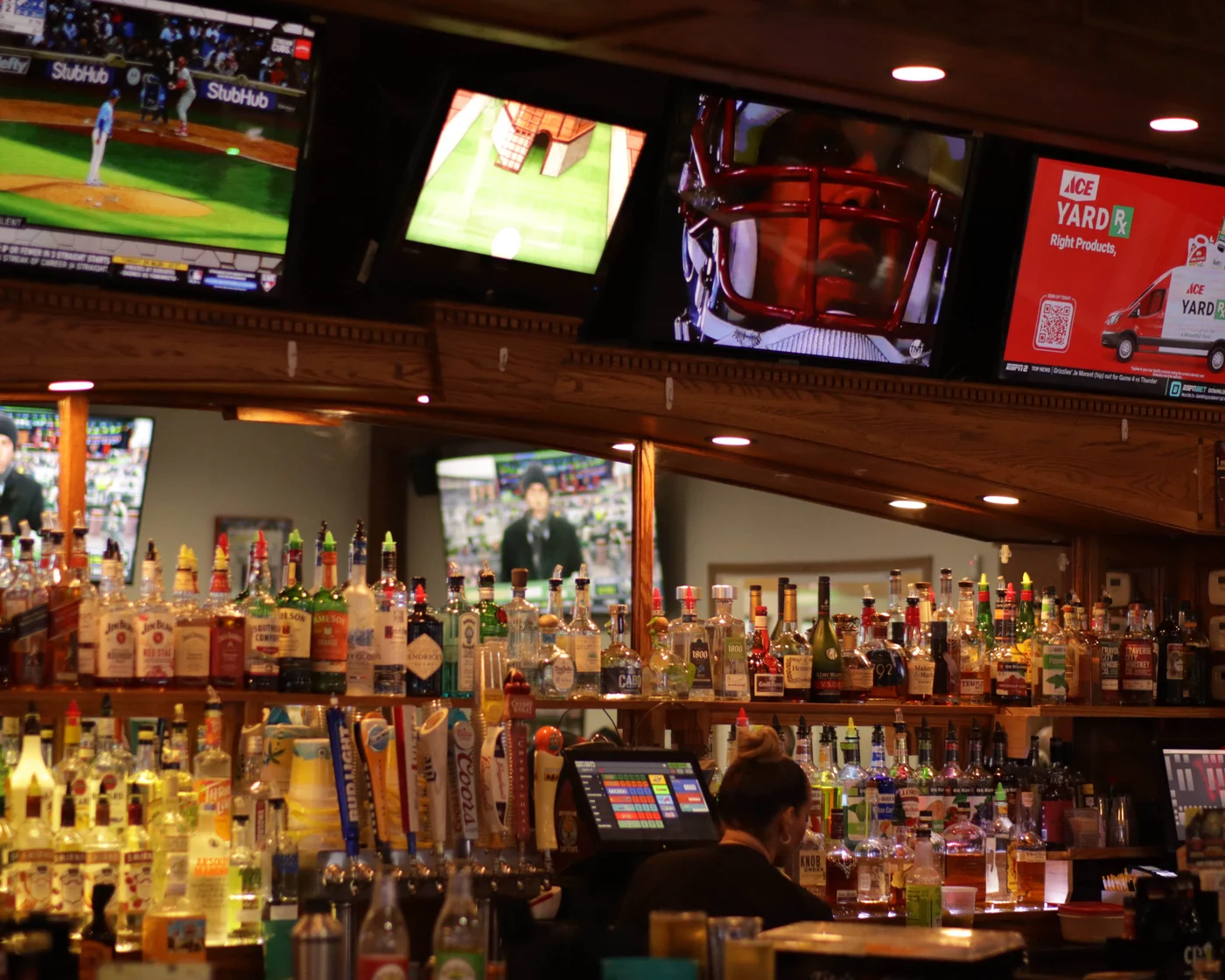 The bar at CJ’s, with bottles, wood counters and televisions