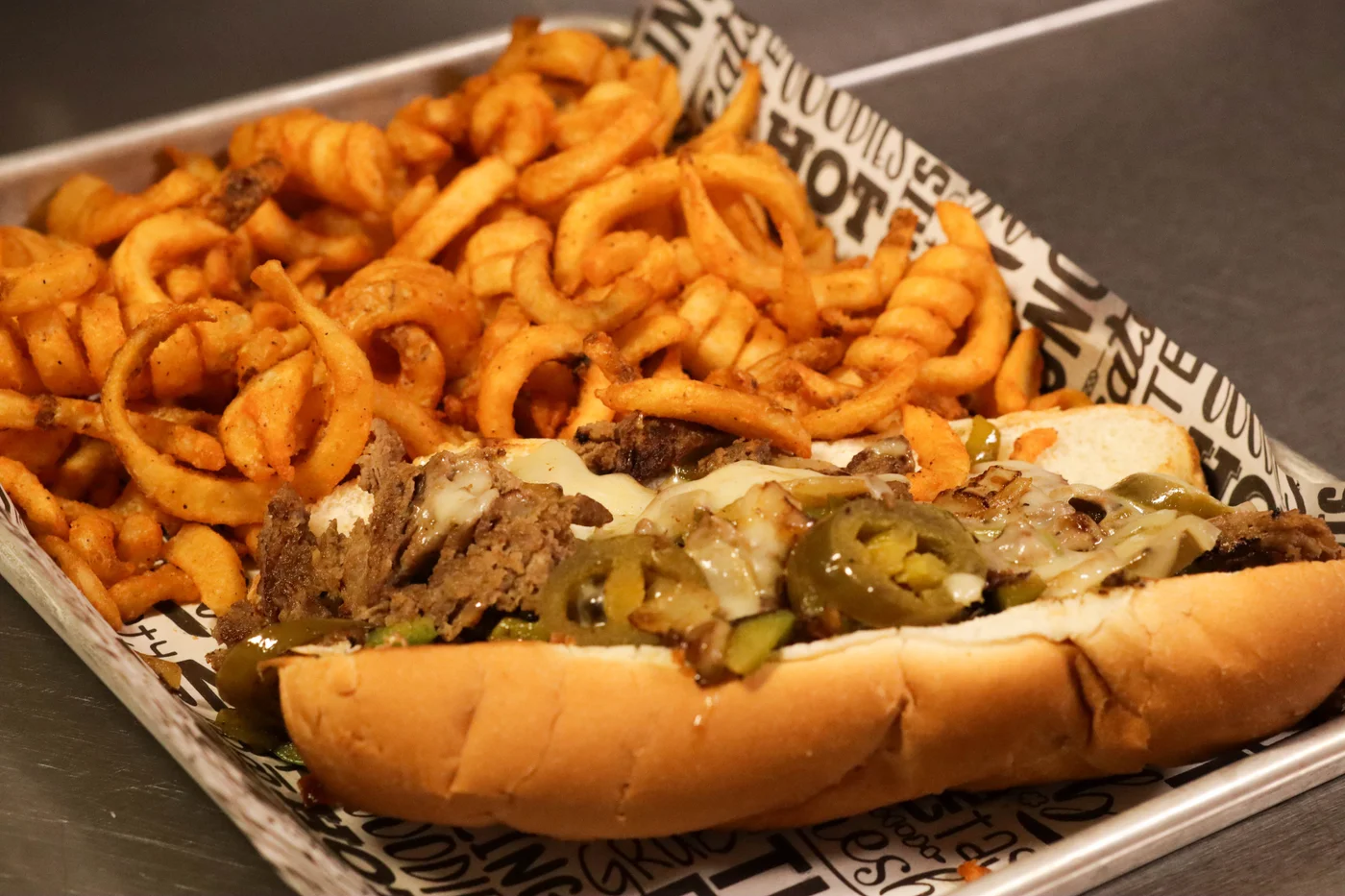 CJ’s steak sandwich with melted cheese, peppers and curly fries
