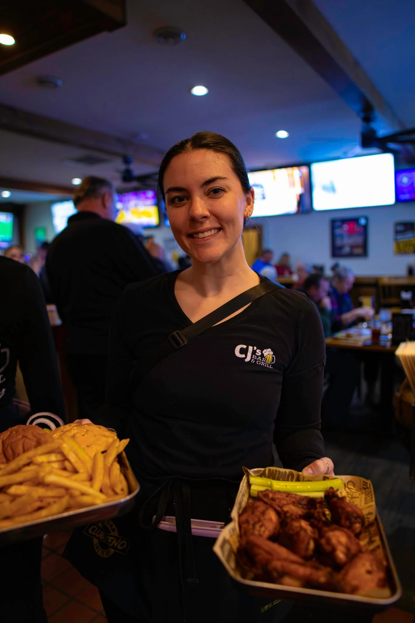 A smiling CJ’s team member serving burgers and ribs